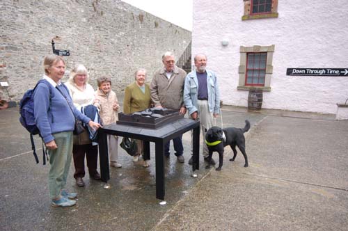 Four women and two men stand around the tactile bronze model of Down County Museum. The man at the right of the picture has a Guide Dog with him.